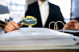 man in suit reviewing documents with magnifying glass